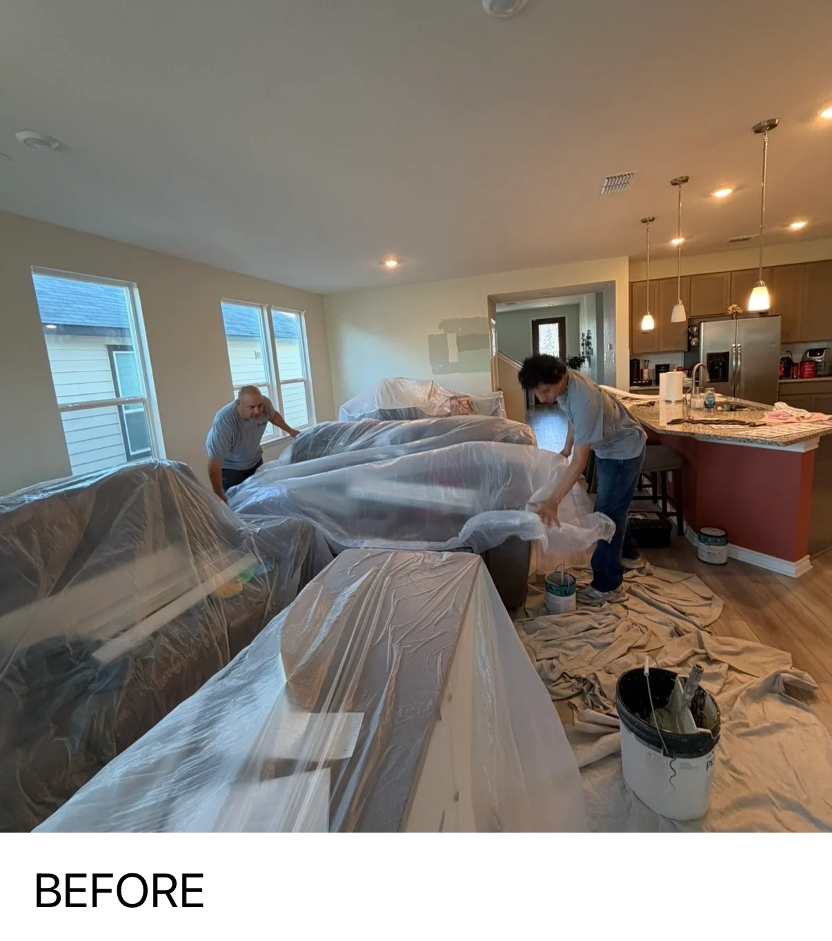 Two painters preparing interior space with protective coverings before painting project