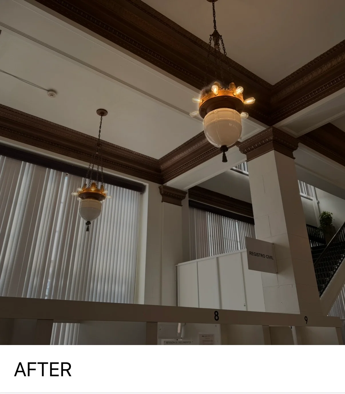 Historic interior with dark wood ceiling beams, white walls, and restored pendant lighting fixtures