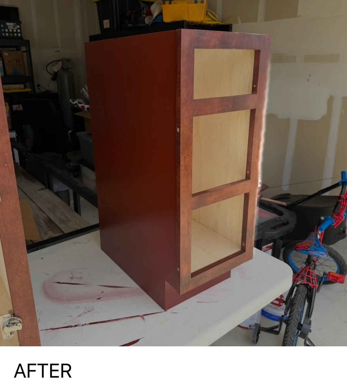 Burgundy painted wooden cabinet with natural wood trim and three light wood panel doors