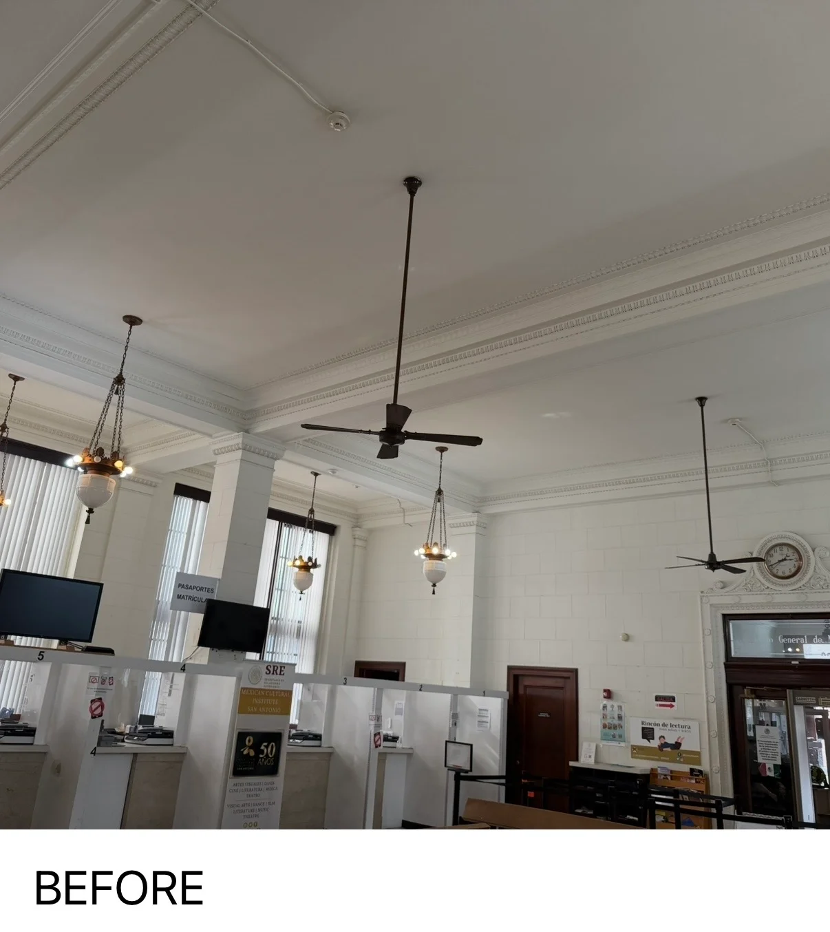 Historic commercial interior with painted white coffered ceiling, crown molding, and pendant lighting fixtures