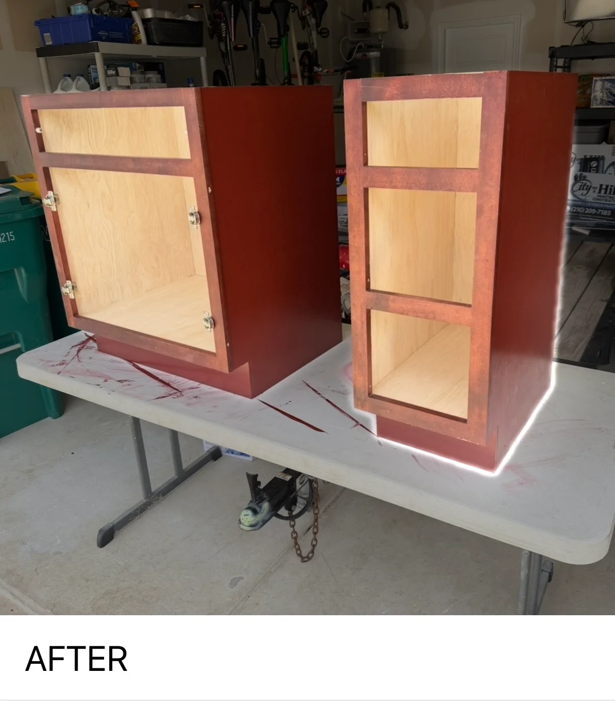 Two burgundy painted wooden cabinets with natural wood interior panels and doors