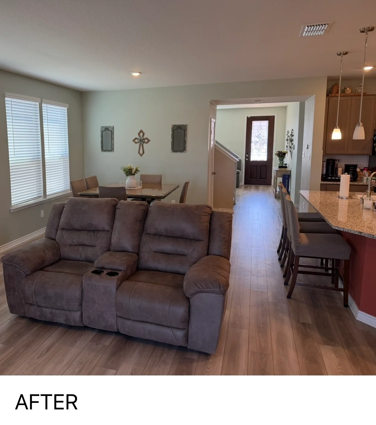 Freshly painted open-concept living room with gray reclining sofa, dining table, and neutral wall colors
