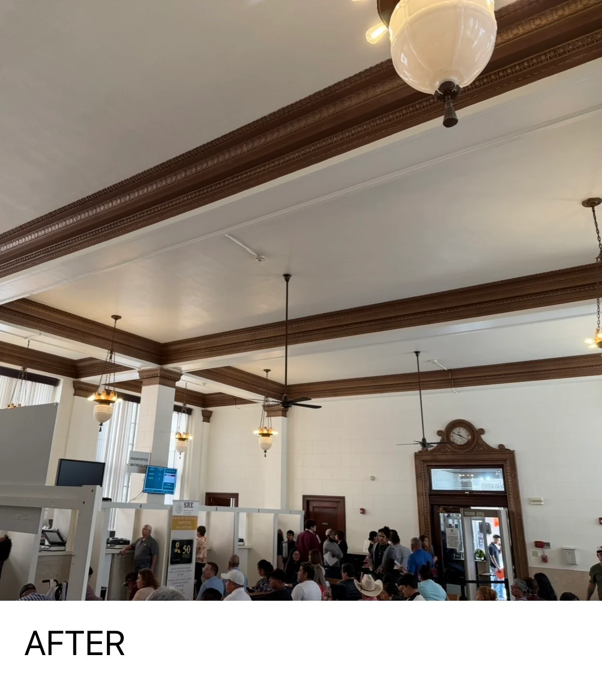 Historic building interior with painted white ceiling, dark wood beams, and pendant lights