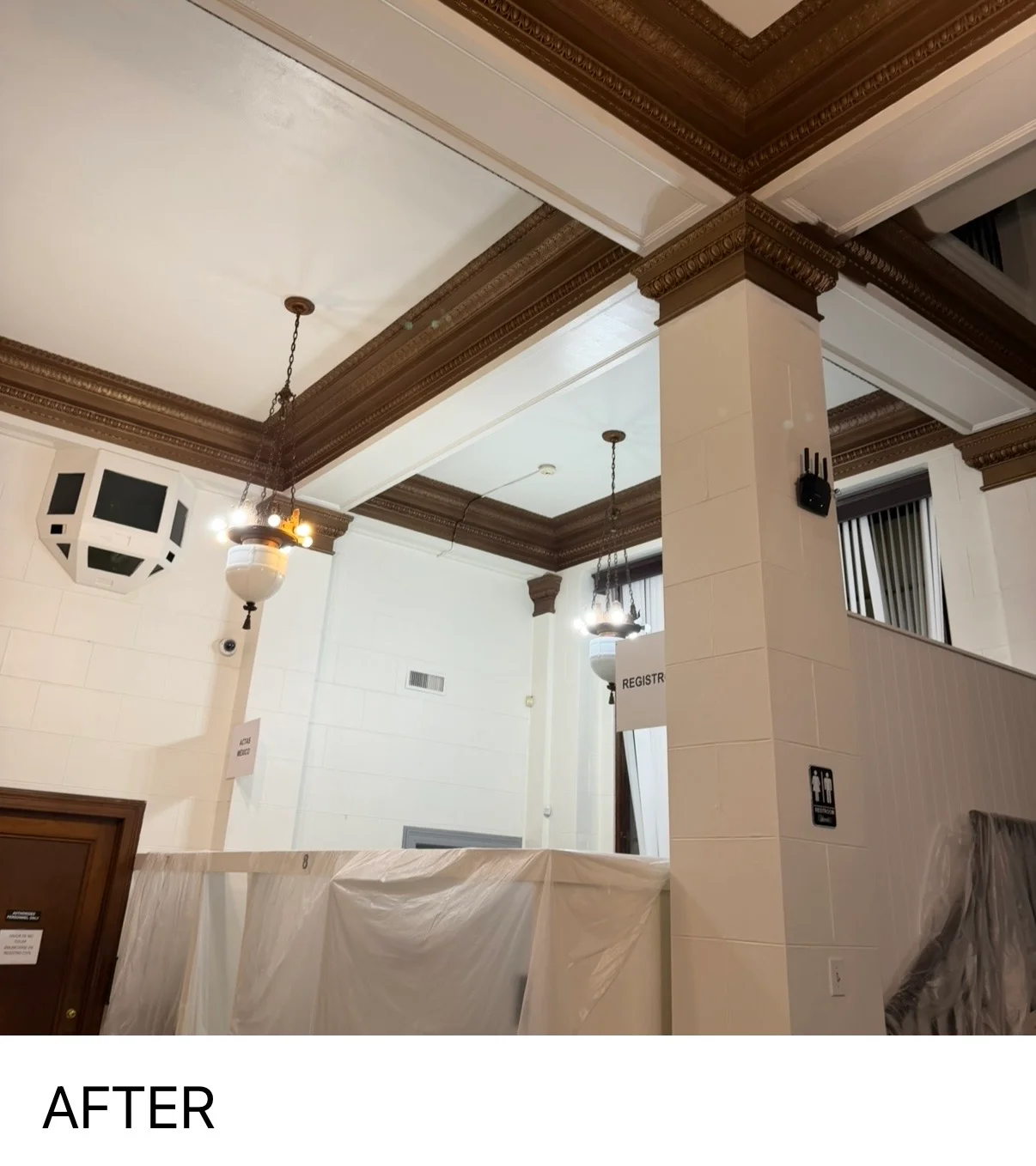 Commercial interior with white painted walls, ornate dark wood ceiling beams, and pendant lighting
